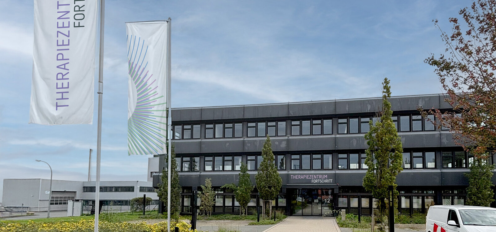 Außenansicht des Praxisgebäudes in Erlangen-Eltersdorf mit Fahnen
